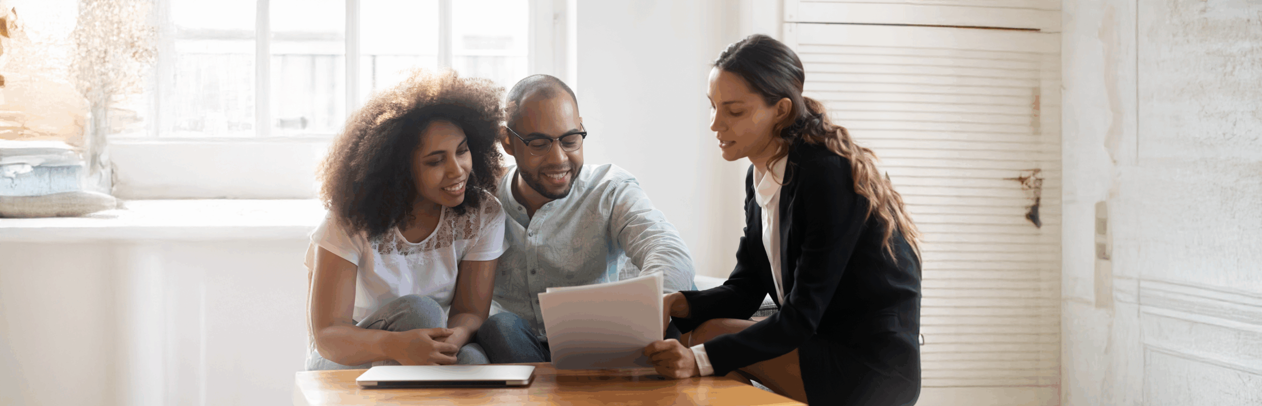 Couple at meeting with agent discussing contract terms.
