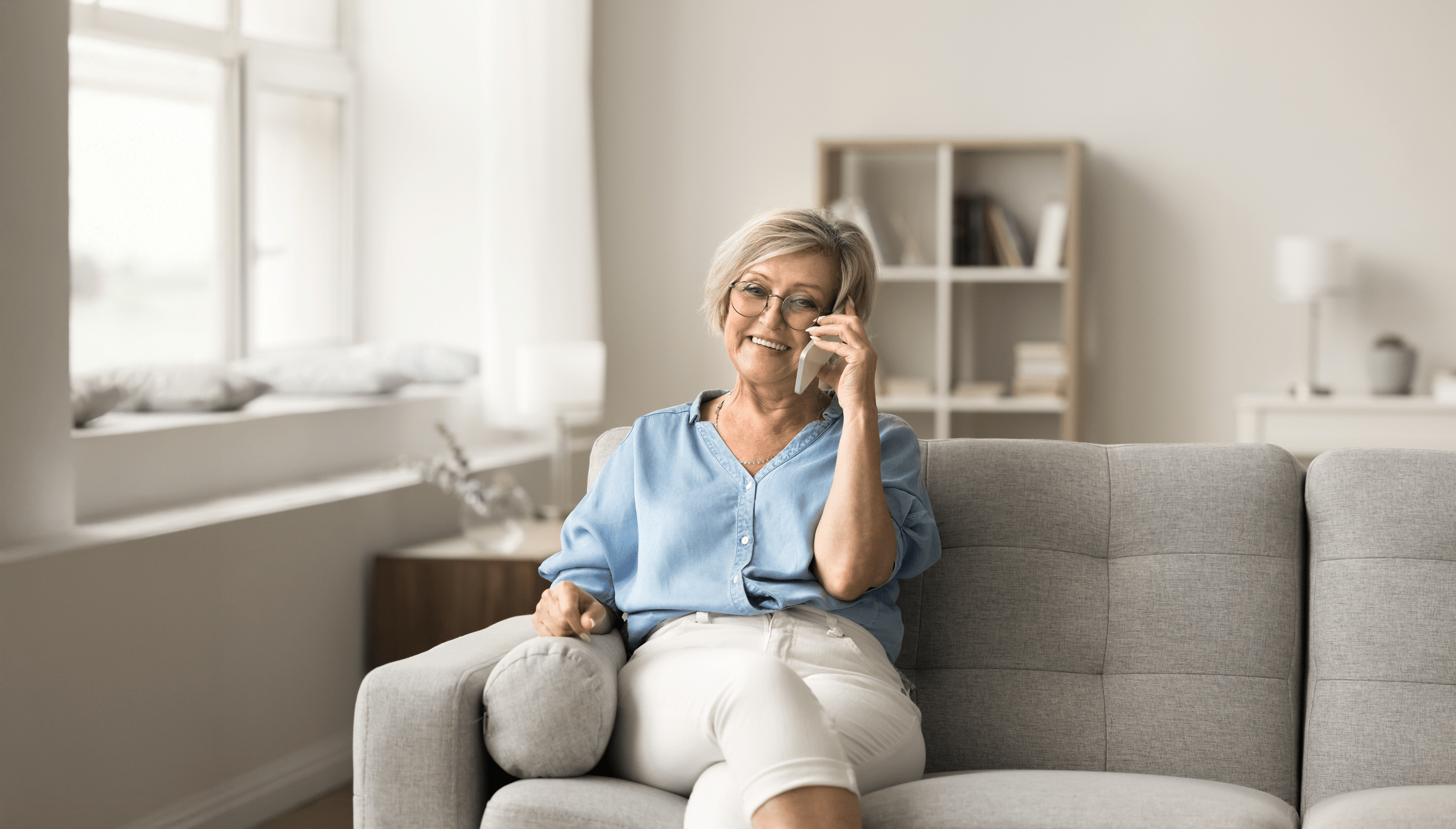 A woman sitting on a couch, engaged in a conversation on her phone.